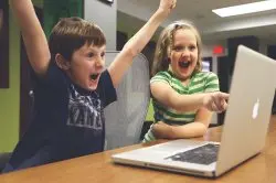 Excited happy kids pointing at computer monitor