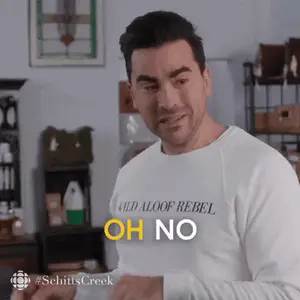 A Man Wearing A White Sweater With The Words `` Oh No '' On It Is Standing In A Room .