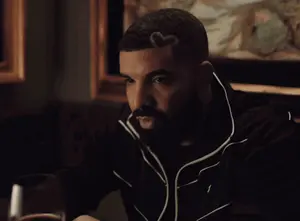 A Man With A Beard Is Sitting At A Table Holding A Glass Of Wine