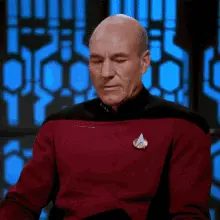 A Bald Man Wearing A Red Sweater With A Star Trek Logo On His Chest