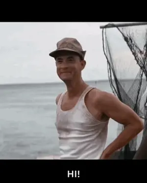 A Man Wearing A Hat And A White Tank Top Stands In Front Of A Body Of Water And Says Hi