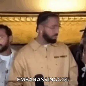 A Man With A Beard Is Standing In Front Of A Microphone And Talking Into It .