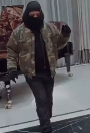 A Man Wearing A Ski Mask And A Camouflage Jacket Is Dancing On A Stage .