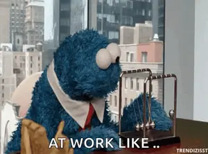 A Cookie Monster Is Sitting At A Desk With A Newton 'S Cradle And Says At Work Like
