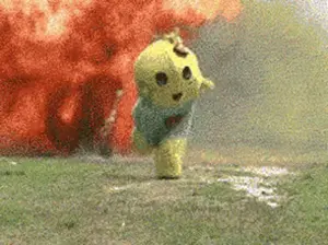 A Yellow Teddy Bear Is Running In Front Of An Explosion In A Field .