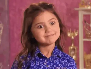 A Little Girl Is Making A Funny Face While Wearing A Blue Shirt With A Leopard Print .