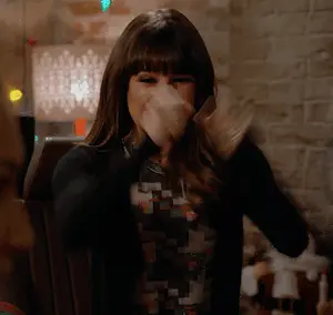 A Woman Covering Her Mouth With Her Hand While Wearing A Black Sweater