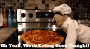 A Stuffed Animal In A Chef 'S Hat Is Cooking A Pizza On A Stove
