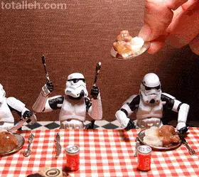 Storm Trooper Action Figures Sitting At A Table With Plates Of Food