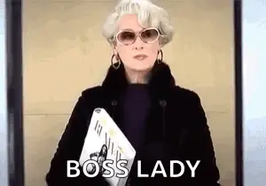 A Woman Wearing Sunglasses And A Fur Coat Is Holding A Magazine And Says Boss Lady .