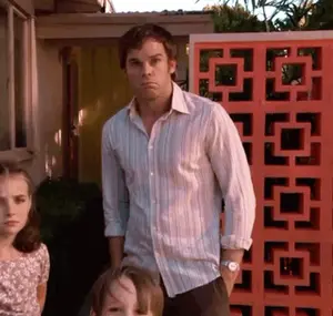 A Man In A Striped Shirt Stands In Front Of A Red Wall