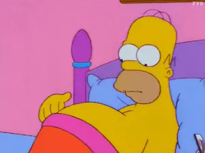 Homer Simpson Is Laying In A Bed With A Pink Blanket