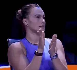 A Woman In A Blue Tank Top Is Clapping Her Hands In A Dark Room .