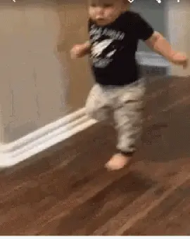A Baby Is Walking On A Wooden Floor With A Piece Of Toilet Paper .