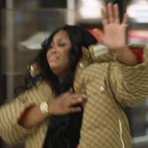 A Woman In A Gucci Jacket Is Waving Her Hand In The Air