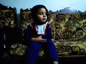 A Little Boy Is Sitting On A Couch With A Floral Pattern