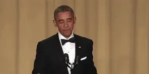 Barack Obama Is Holding A Microphone And Covering His Mouth .