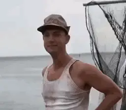 A Man Wearing A Hat And Tank Top Is Standing In Front Of A Fishing Net .