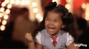 A Little Girl Is Laughing And Crying While Wearing A Tie And A Bow .