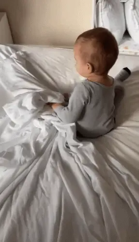 A Baby Laying On A Bed With A White Blanket