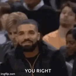 A Man With A Beard Is Sitting In A Crowd Of People And Looking At The Camera .