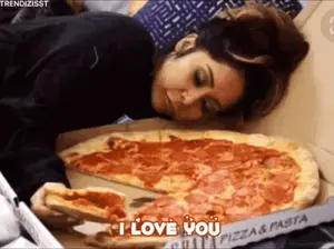 A Woman Is Laying On A Bed Eating A Large Pizza And Saying I Love You