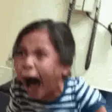 A Little Girl Is Crying With Her Mouth Open In A Hospital Room .