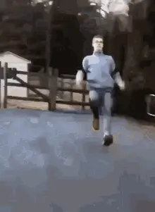 A Man In A Blue Shirt And Jeans Is Running Down A Street .