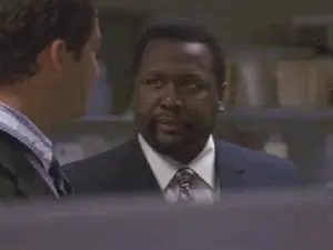 Two Men In Suits And Ties Are Talking To Each Other In An Office .