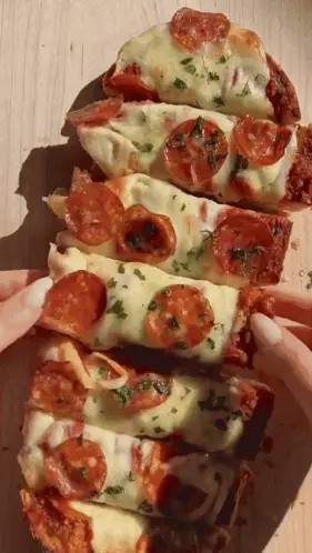 A Stack Of Pizza Slices With Pepperoni And Cheese On A Wooden Table