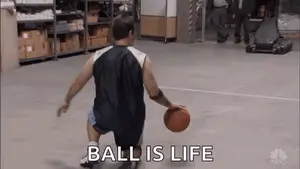 A Man Is Dribbling A Basketball On A Court In A Warehouse And Saying `` Ball Is Life '' .