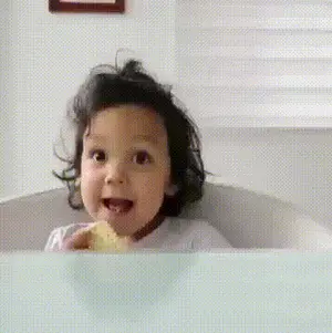 A Little Girl Is Sitting In A Bathtub And Eating A Piece Of Food