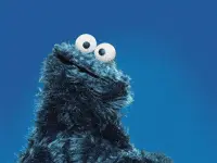 A Cookie Monster From Sesame Street Is Smiling And Looking At The Camera