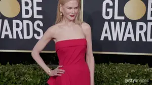 A Woman In A Red Strapless Dress Is Standing In Front Of A Sign That Says " Be Glob Awards "