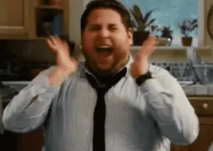 A Man In A Shirt And Tie Is Screaming With His Hands In The Air .