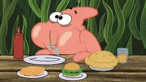Patrick Star Is Sitting At A Table With Plates Of Food .