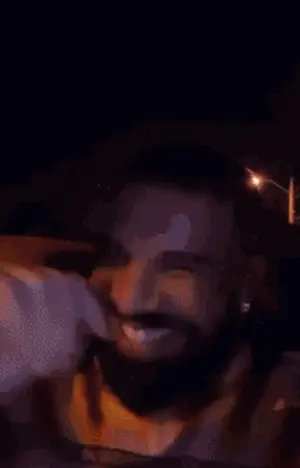 A Man With A Beard Is Sitting In The Back Seat Of A Car And Smiling .