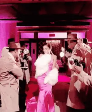 A Woman In A Pink Dress Is Being Photographed By Men