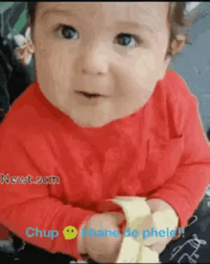 A Baby In A Red Shirt Is Holding A Banana And Says Chup