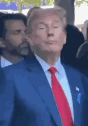 A Man In A Blue Suit And Red Tie Stands In Front Of A Crowd .