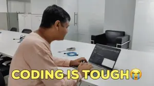 A Man Sits At A Table With A Laptop And The Words " Coding Is Tough " On The Bottom