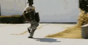 A Man Is Running Down A Sidewalk Carrying A Briefcase