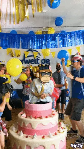 A Group Of People Are Dancing In Front Of A Large Cake With A Monkey On It