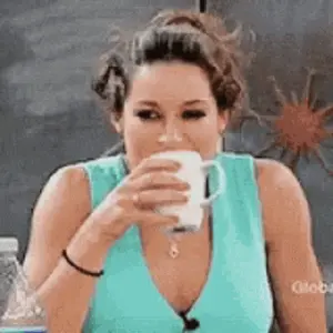 A Woman In A Blue Tank Top Is Drinking From A White Mug