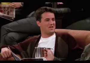 A Man Sits On A Couch Reading A Magazine And Holding A Cup