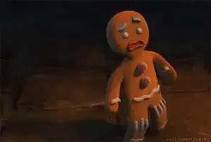 A Gingerbread Man From Shrek Is Standing On A Wooden Floor .