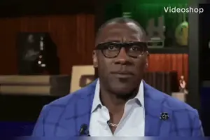 A Man Wearing Glasses And A Blue Jacket Is Sitting In Front Of A Microphone With The Word Videoshop On The Bottom