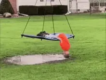 A Child Is Doing A Handstand On A Swing Over A Puddle Of Water