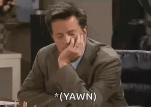 A Man In A Suit And Tie Is Sitting At A Desk With His Hand On His Chin And Says `` Yawn '' .