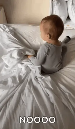 A Baby Is Laying On A Bed With A White Blanket And The Word Nooo Written On It